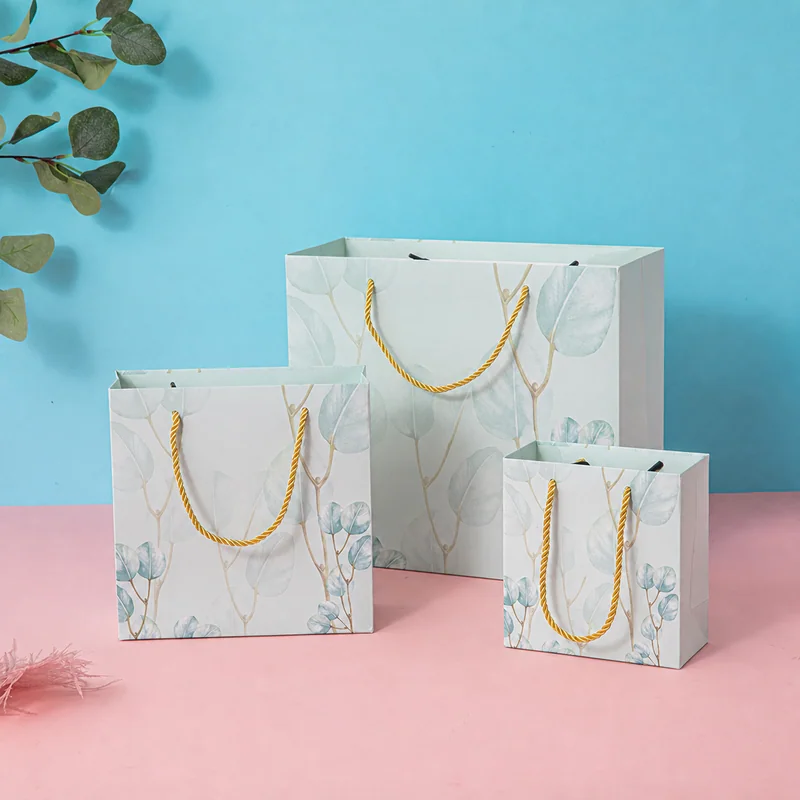 Three botanical patterned gift bags with gold rope handles